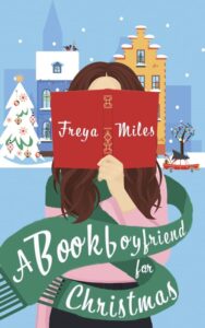 Buchcover von 'A Bookboyfriend for Christmas' mit einer Frau, die ein rotes Buch hält, umgeben von winterlicher Dekoration.