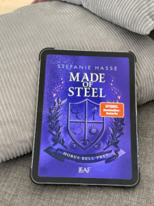 Lila Buchcover „MADE OF STEEL“ von STEFANIE HASSE mit „SPIEGEL Bestseller-Autorin“-Badge, grafischem Wappen und Funken-Design.